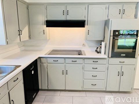 A kitchen with white cabinets and a black fridge.