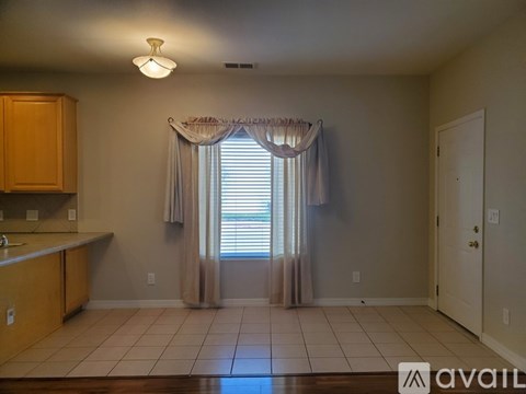 A kitchen with wooden cabinets and a window with curtains.