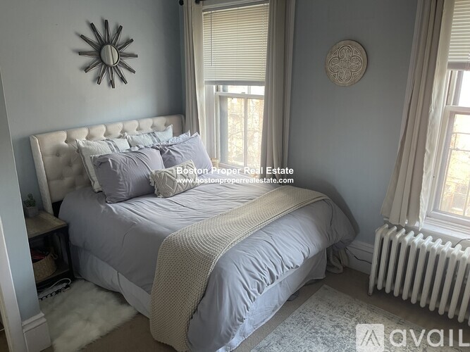 A bedroom with a large bed and a decorative sunburst mirror on the wall.