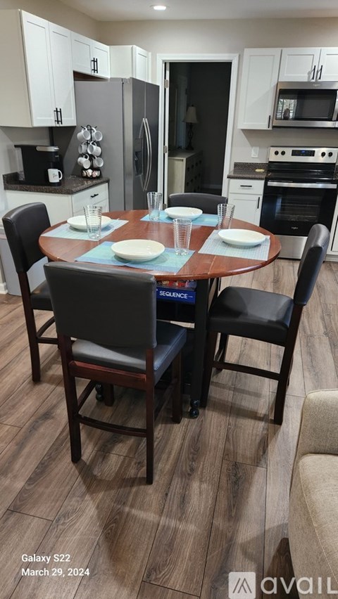 A dining room with a table set for two and chairs around it.