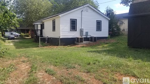 A small white house with a black door and a black awning.