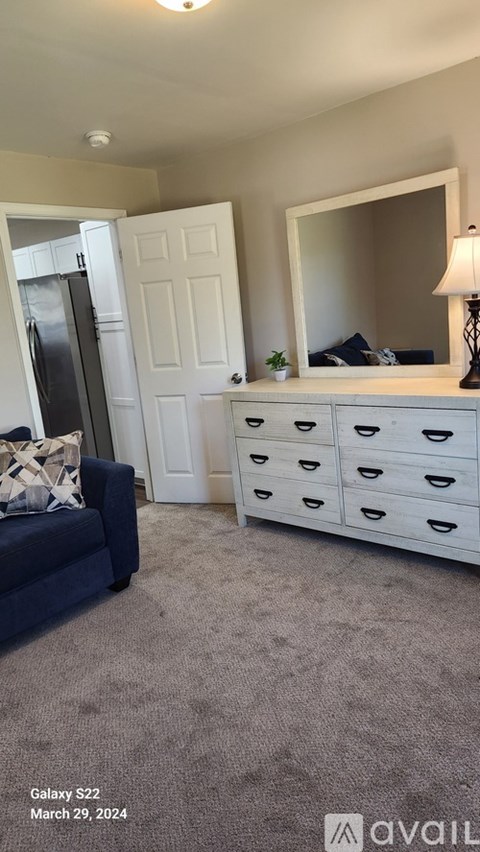 A bedroom with a white dresser and a blue couch.