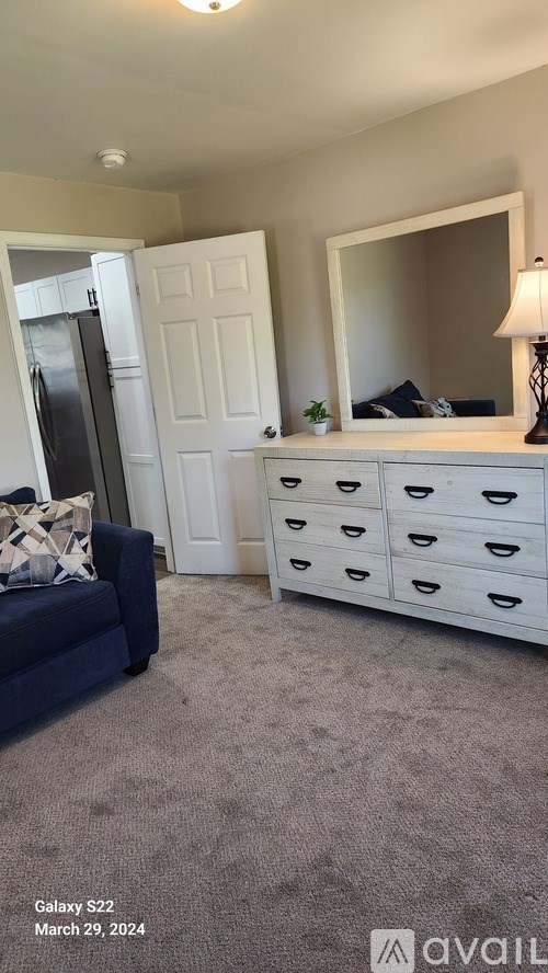 A bedroom with a white dresser and a blue couch.