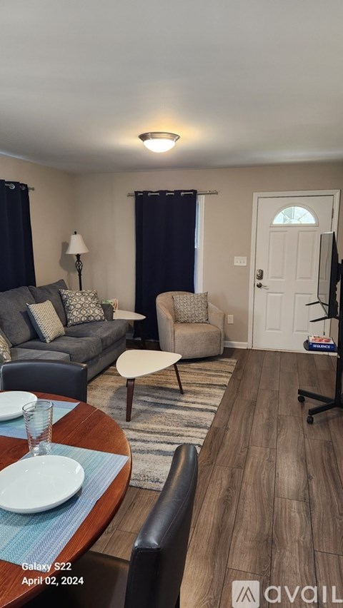 A living room with a couch, chair, and a dining table set for two.