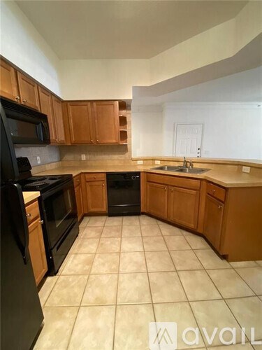 A kitchen with wooden cabinets and black appliances.