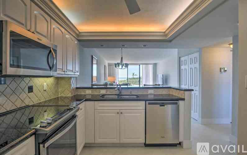 A kitchen with white cabinets and a black countertop.