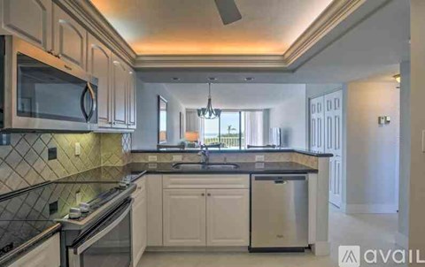 A kitchen with white cabinets and a black countertop.