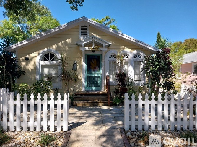 A small yellow house with a white picket fence in front.