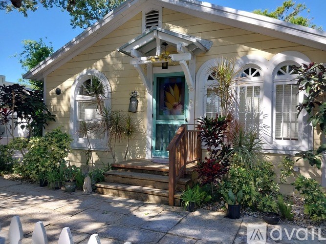 A yellow house with a green door and a wooden staircase leading to the door.