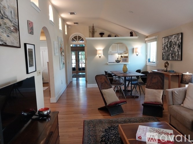 A living room with a couch, chairs, and a television.
