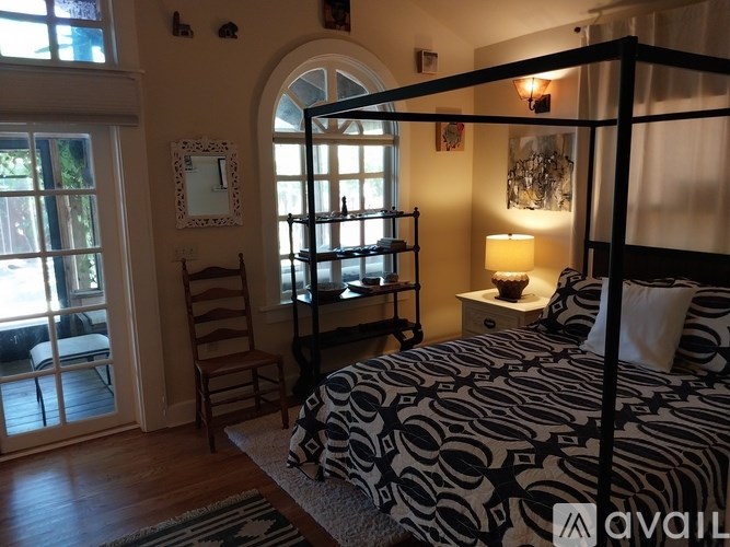 A bedroom with a four poster bed and a chair by a window.