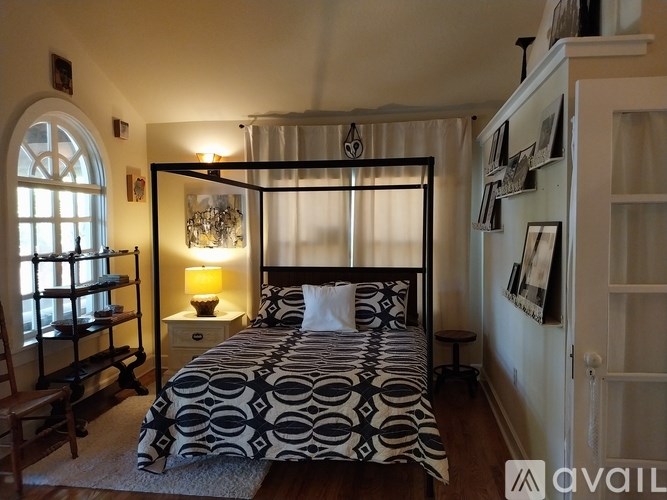 A bedroom with a four poster bed and a window with blinds.