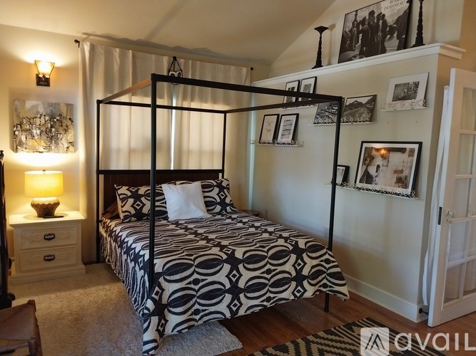 A bedroom with a four poster bed and a lamp on a side table.