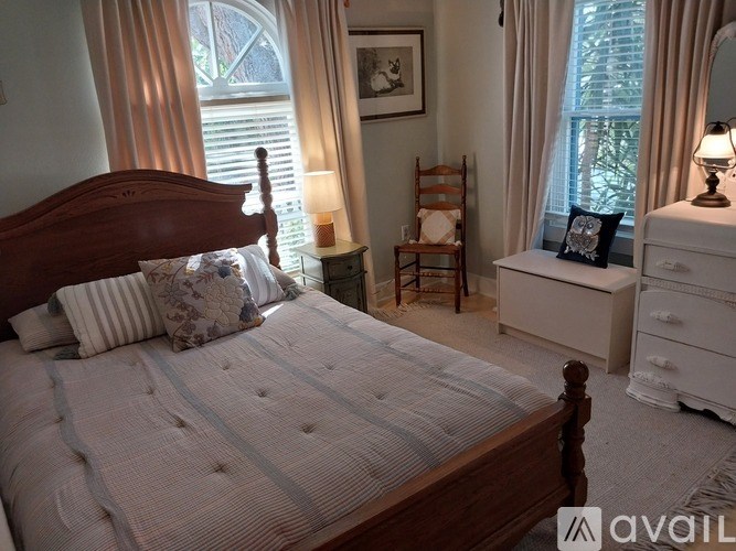 A bedroom with a large bed, a nightstand, and a dresser.