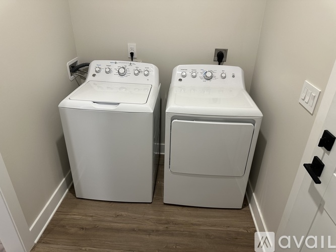 Two white front loading washing machines in a small laundry room.