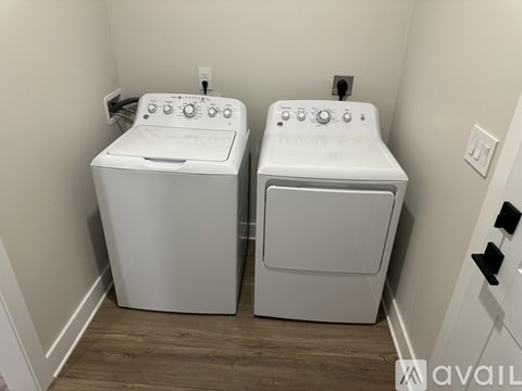 Two white front loading washing machines in a small laundry room.