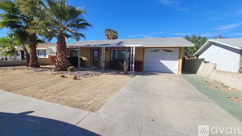 A house with a driveway and palm trees in front.