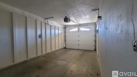 A long, narrow room with a white door at the end and a wall-mounted speaker.