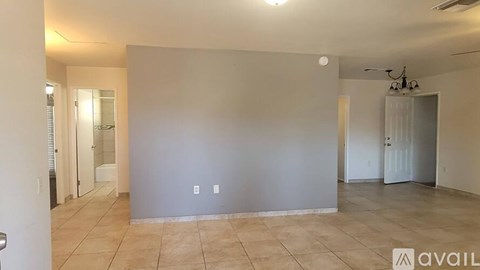 A spacious room with tiled flooring and a ceiling fan.