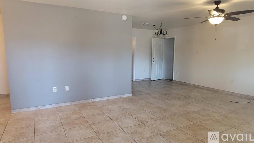 A room with a ceiling fan and a door in the background.