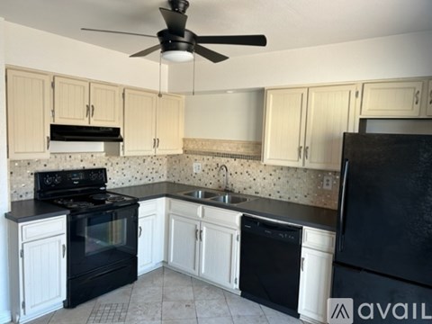 A kitchen with black appliances and white cabinets.