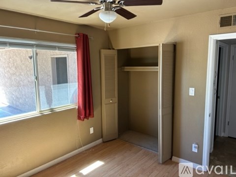 A room with a ceiling fan and a red curtain.