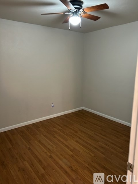 A room with a ceiling fan and wooden flooring.
