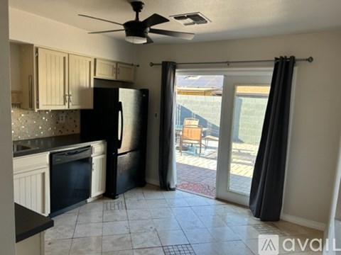 A kitchen with a black refrigerator and a fan on the ceiling.