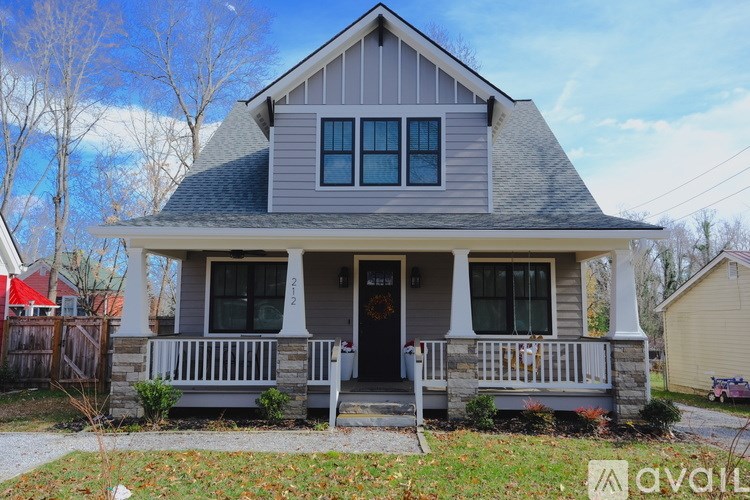 A house with a grey front porch and a red awning is for sale.