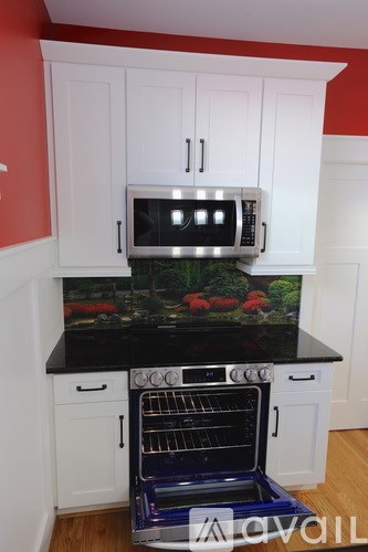 A kitchen with white cabinets and a black countertop with a microwave on top.