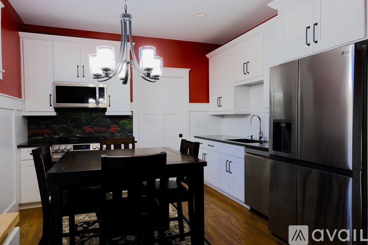 A kitchen with a table and chairs in front of a stainless steel refrigerator.