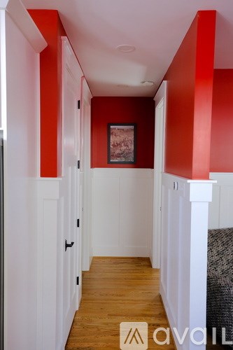A hallway with white walls and a red accent wall.