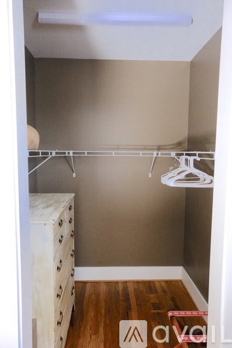 A small closet with a white hanger and a white dresser with black dots.