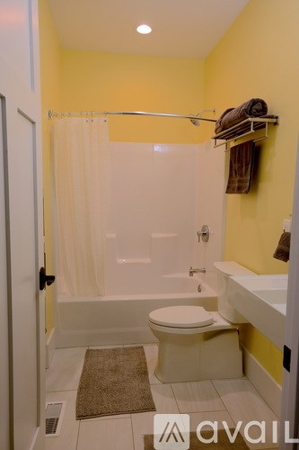 A bathroom with yellow walls has a white toilet and a walk-in shower.