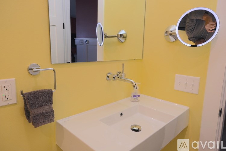 A bathroom with a white sink and a yellow wall.