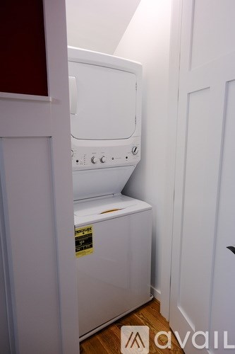 A white dishwasher is in a narrow space between a wall and a cabinet.