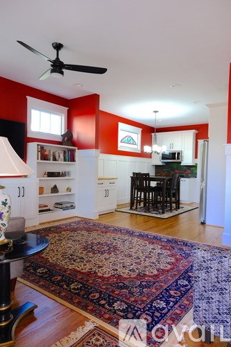 A living room with a rug on the floor and a fan on the ceiling.