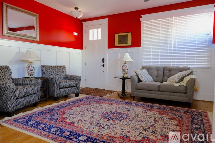 A living room with a grey couch, two chairs, and a rug.