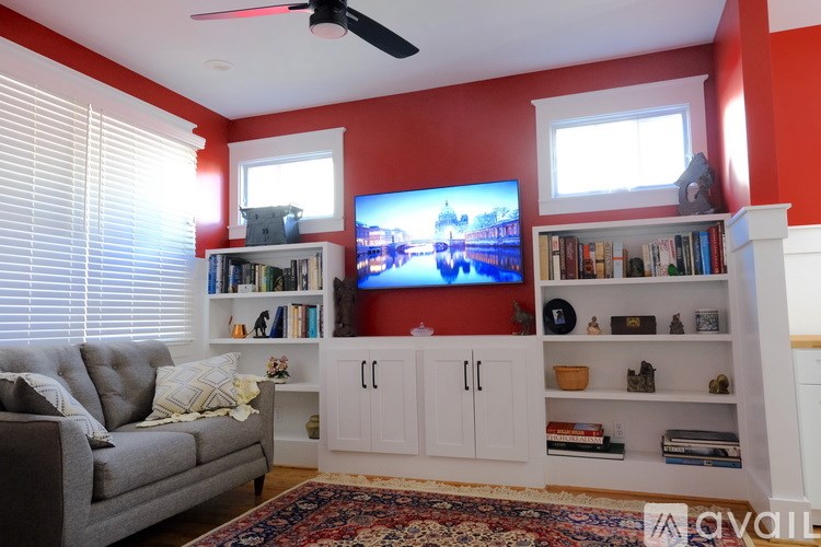 A living room with a grey couch, a television, and a bookshelf.