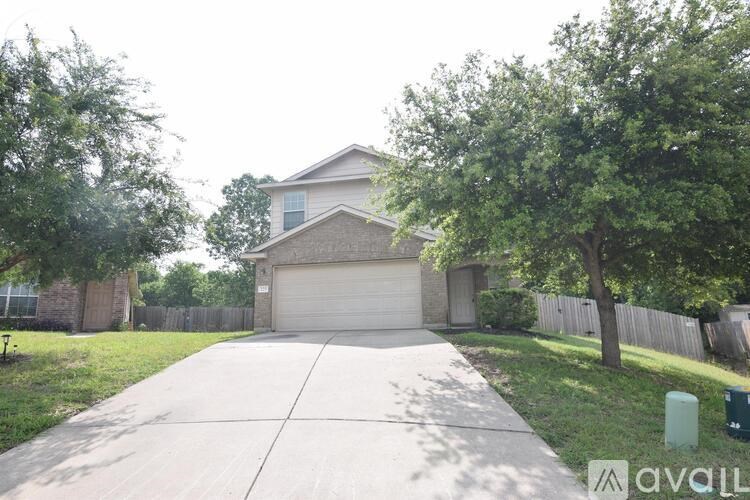 A house with a driveway and a tree in front of it.