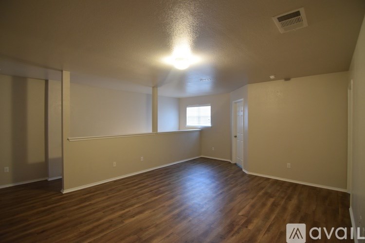A spacious room with wooden floors and a window letting in natural light.