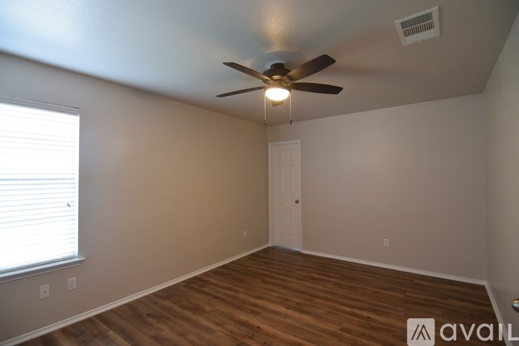 A room with a ceiling fan and wooden flooring.