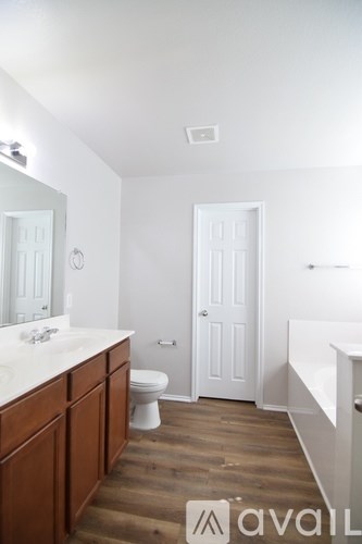 A bathroom with a toilet, sink, and wooden floors.