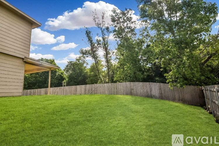 A two-story house with a front porch and a fence in the background.