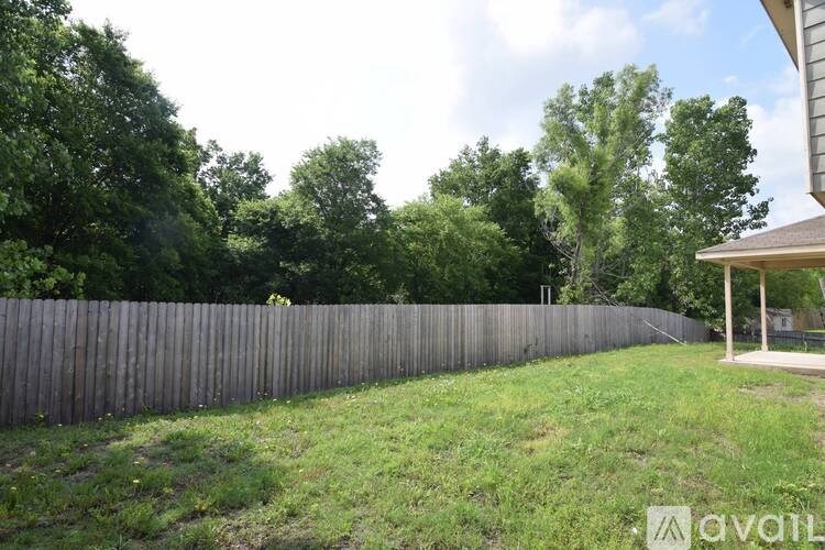 A backyard with a wooden fence and a house in the background.