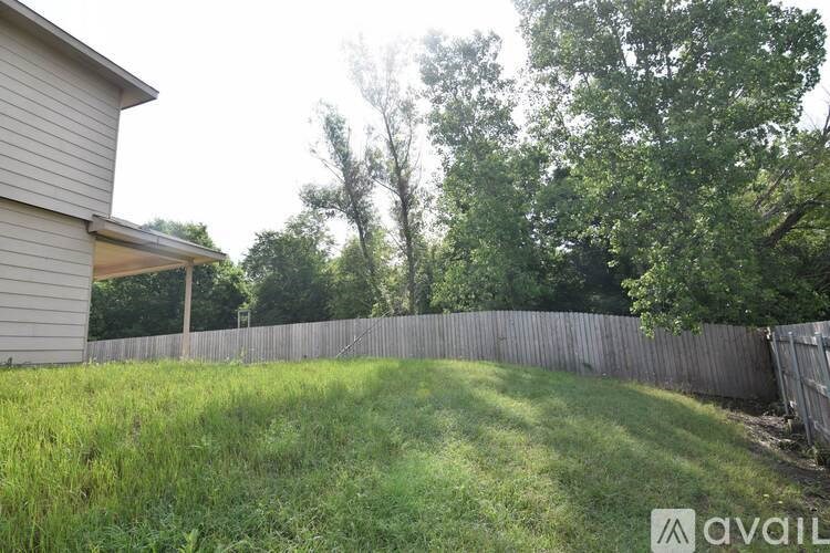 A backyard with a wooden fence and a house in the background.