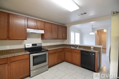 A kitchen with brown cabinets and a black dishwasher.