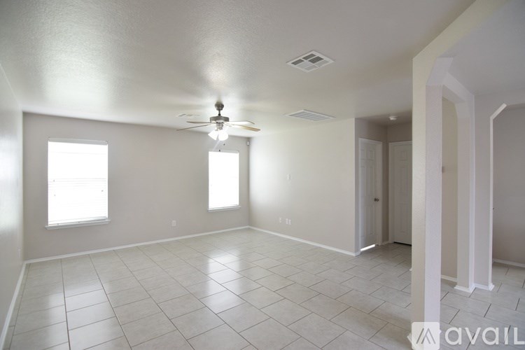 A spacious room with a ceiling fan and two windows.