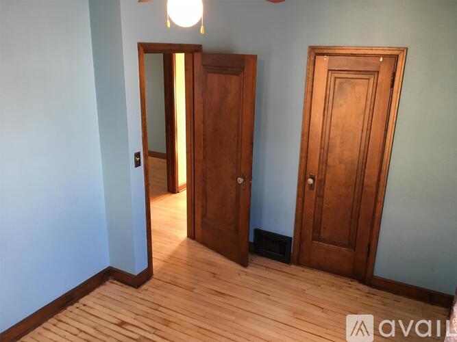 A room with a wooden floor and two wooden doors.