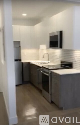 A modern kitchen with stainless steel appliances and wooden flooring.
